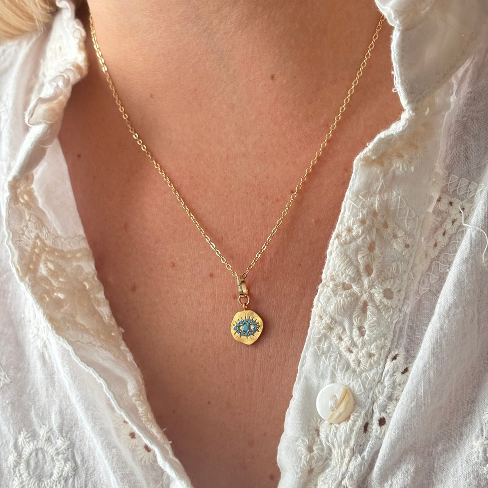 close up photo of a boho evil eye necklace showing fine enamel and gold detailing